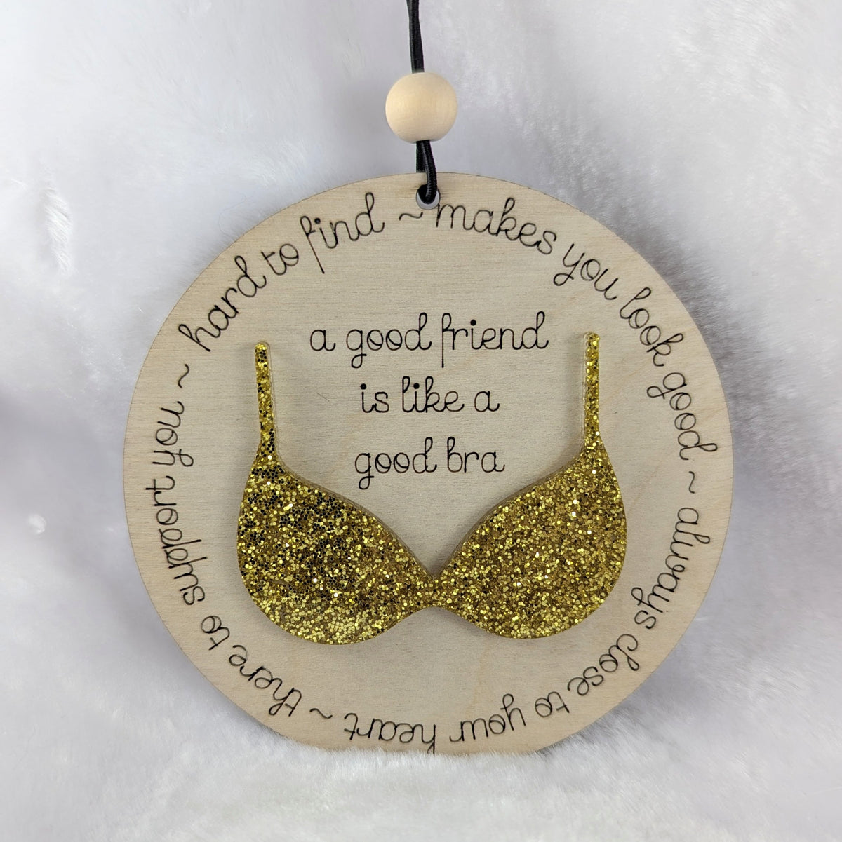 Friendship ornament with a gold bra. Reads: A good friend is like a good bra. 