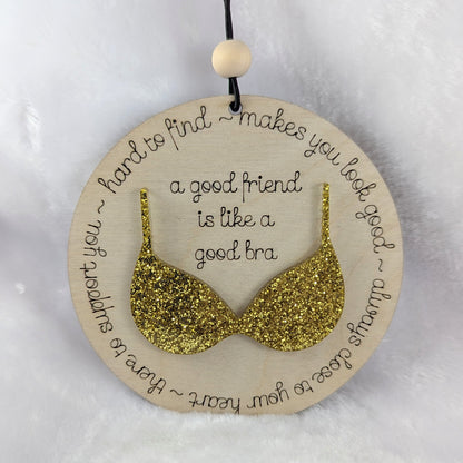 Friendship ornament with a gold bra. Reads: A good friend is like a good bra. 